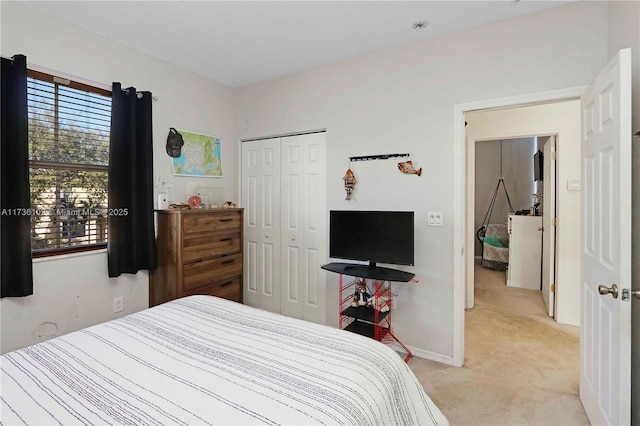 bedroom with baseboards, a closet, and light colored carpet