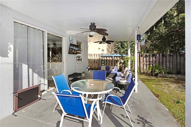 view of patio featuring fence, outdoor dining area, and a ceiling fan