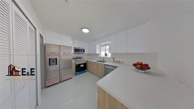 kitchen featuring stainless steel appliances, light brown cabinetry, sink, and white cabinets