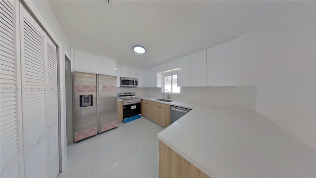 kitchen featuring white cabinetry, sink, stainless steel appliances, and light brown cabinetry