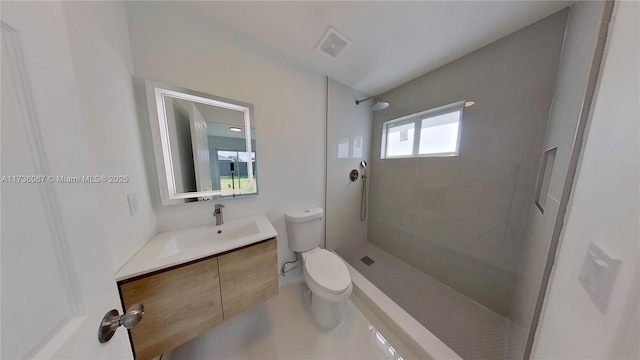 bathroom featuring vanity, toilet, and a tile shower