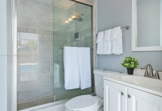 bathroom with a shower with door, vanity, and toilet