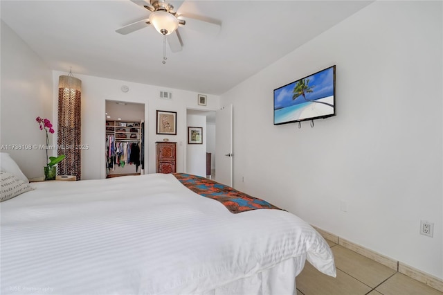 bedroom with a spacious closet, tile patterned floors, and ceiling fan