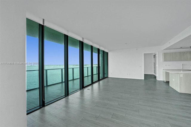 spare room with wood-type flooring, expansive windows, and a water view