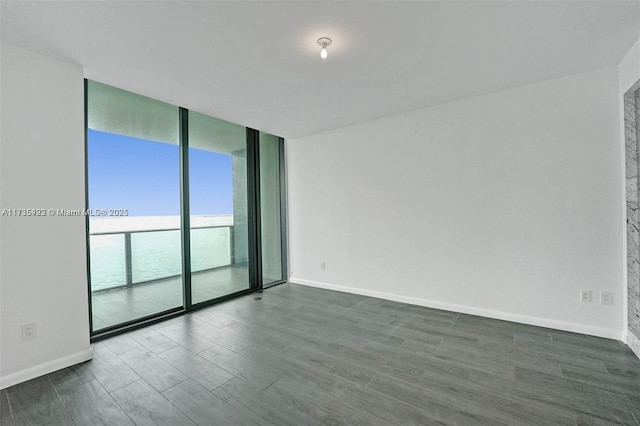 empty room with a water view, dark hardwood / wood-style floors, and a wall of windows