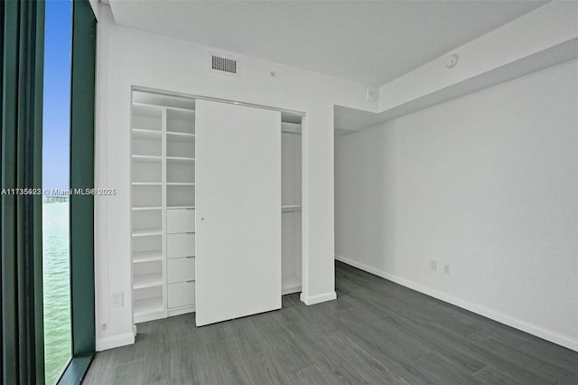 unfurnished bedroom featuring dark wood-type flooring and a closet