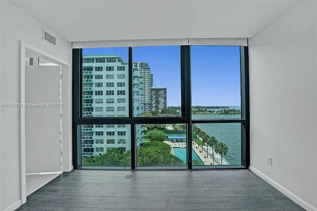 unfurnished room with hardwood / wood-style flooring, expansive windows, and a water view