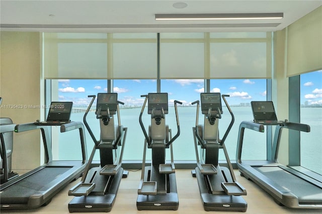 exercise room featuring a water view and a wall of windows