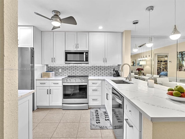 kitchen with sink, appliances with stainless steel finishes, white cabinetry, decorative backsplash, and decorative light fixtures