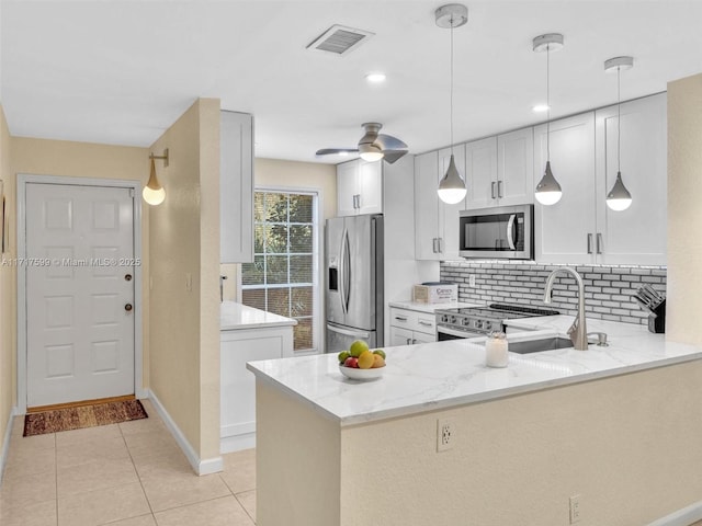 kitchen featuring appliances with stainless steel finishes, kitchen peninsula, light stone countertops, and white cabinets