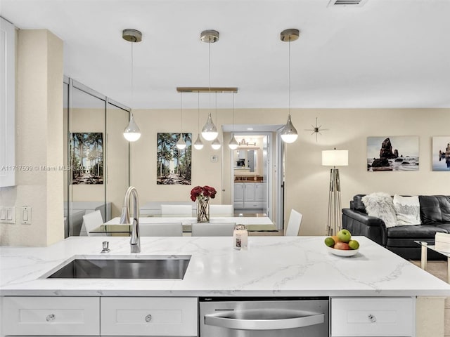 kitchen with white cabinetry, light stone counters, sink, and hanging light fixtures