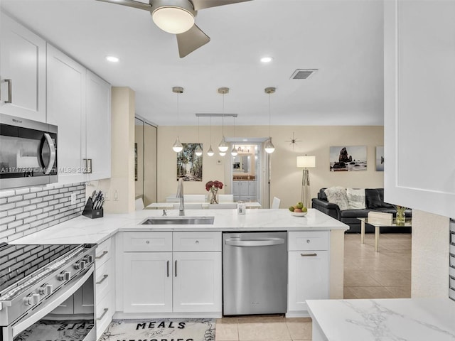 kitchen with sink, white cabinetry, stainless steel appliances, decorative light fixtures, and kitchen peninsula