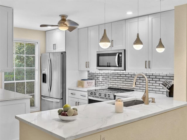 kitchen featuring stainless steel appliances, white cabinets, light stone counters, and kitchen peninsula