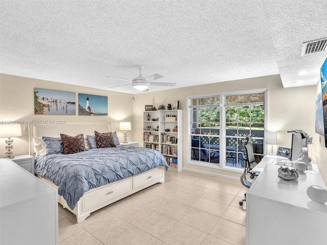 tiled bedroom with ceiling fan and a textured ceiling