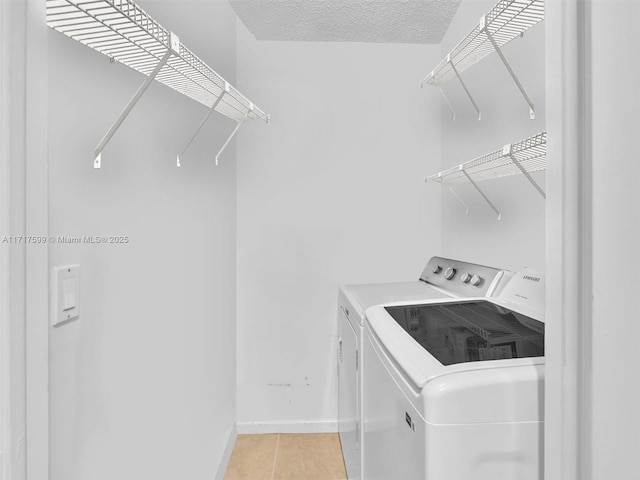 laundry area featuring light tile patterned floors, washer and dryer, and a textured ceiling