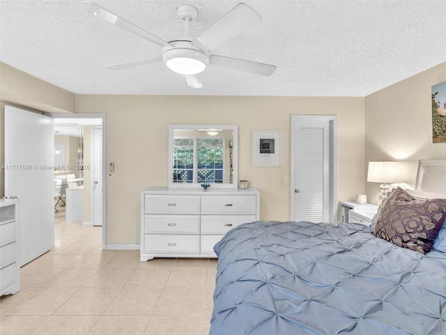 bedroom featuring light tile patterned flooring, ceiling fan, and a textured ceiling