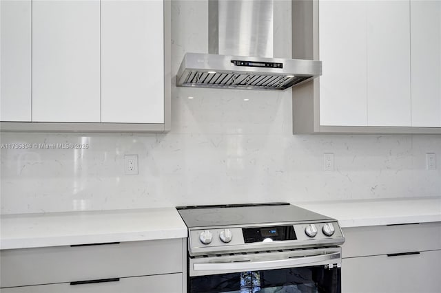 kitchen with electric stove, backsplash, range hood, and white cabinets