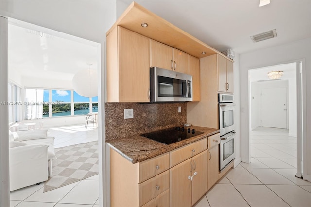 kitchen with tasteful backsplash, stainless steel appliances, stone countertops, and light brown cabinets