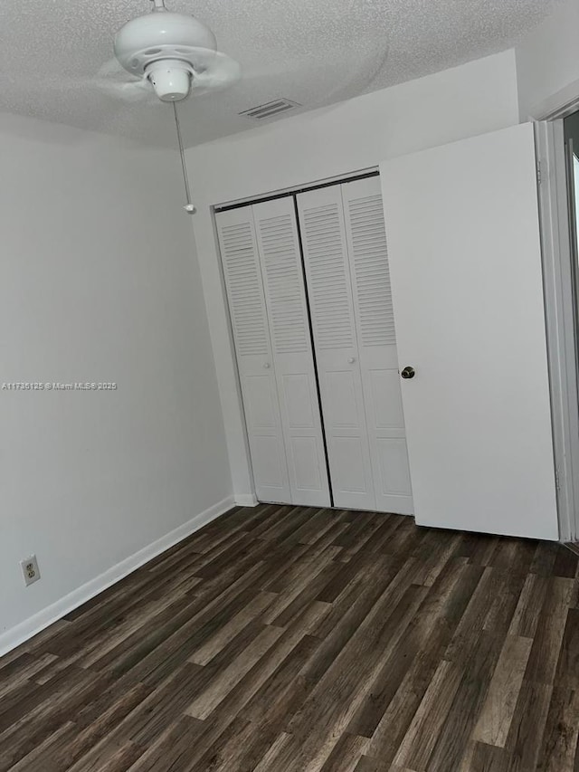 unfurnished bedroom featuring a closet, dark hardwood / wood-style flooring, and a textured ceiling