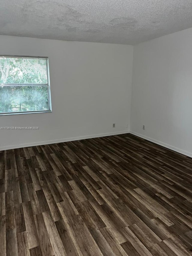 spare room with dark hardwood / wood-style floors and a textured ceiling