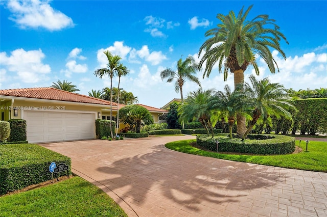 view of front of home featuring a garage, a tiled roof, decorative driveway, and stucco siding