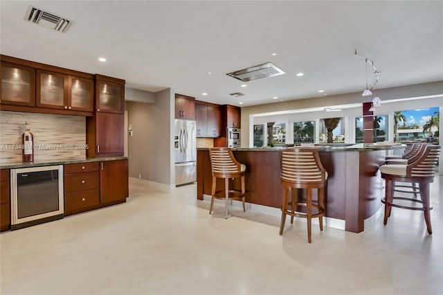 kitchen featuring hanging light fixtures, stainless steel appliances, tasteful backsplash, a kitchen bar, and beverage cooler