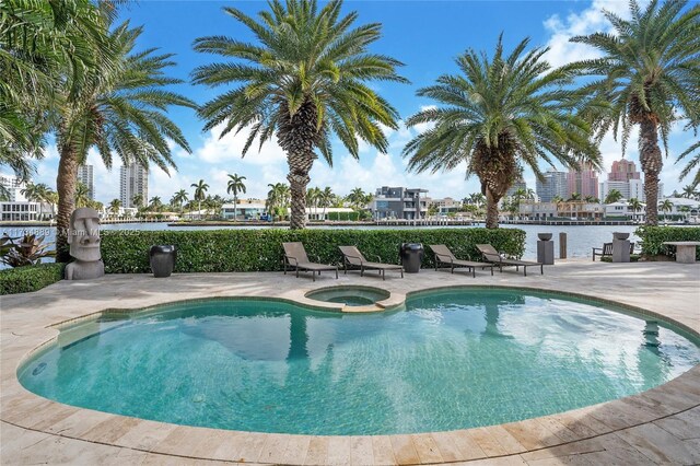 view of pool featuring a patio area, a water view, and an in ground hot tub