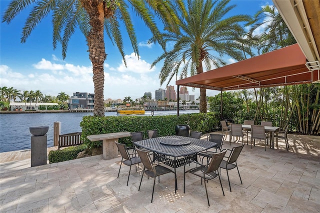 view of patio / terrace with outdoor dining space, a water view, and a city view