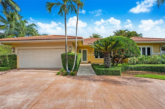 view of front of property with a tiled roof, an attached garage, driveway, and stucco siding