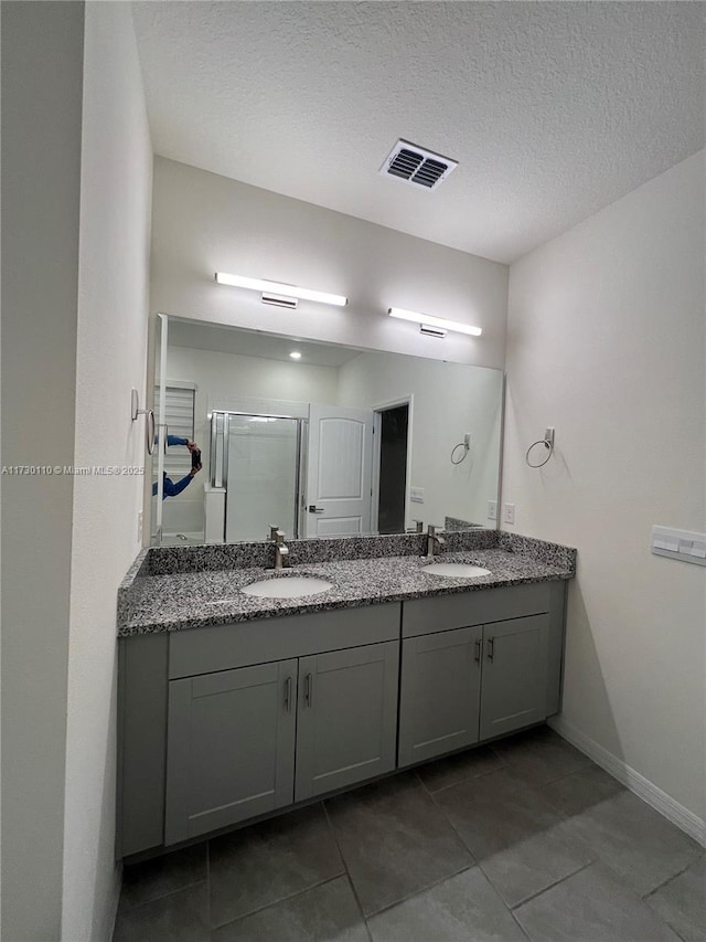 bathroom featuring vanity, tile patterned flooring, a shower with door, and a textured ceiling