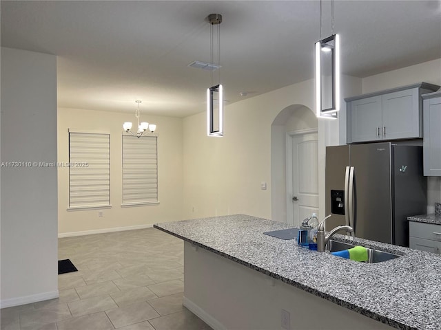 kitchen featuring sink, gray cabinetry, hanging light fixtures, stainless steel refrigerator with ice dispenser, and light stone countertops