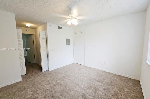 carpeted empty room featuring electric panel and a textured ceiling