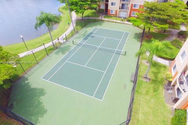 view of sport court with a lawn and a water view