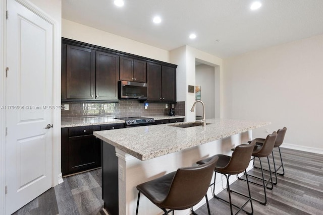 kitchen featuring a kitchen island with sink, sink, a breakfast bar, and appliances with stainless steel finishes