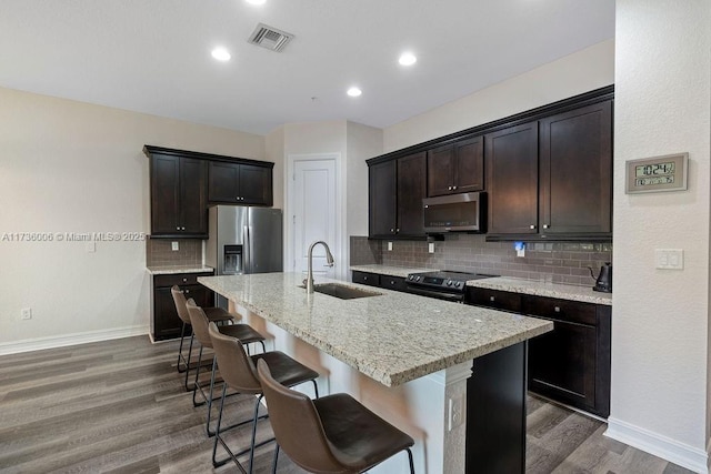 kitchen with appliances with stainless steel finishes, sink, a breakfast bar area, a kitchen island with sink, and dark wood-type flooring