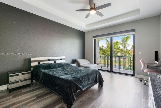 bedroom with hardwood / wood-style flooring, ceiling fan, a tray ceiling, and access to outside