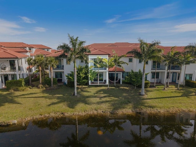 rear view of house with a lawn and a water view