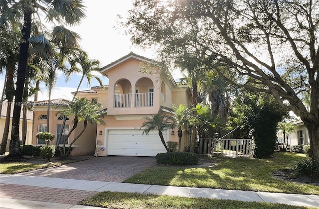 mediterranean / spanish-style house featuring a garage, a front yard, and a balcony