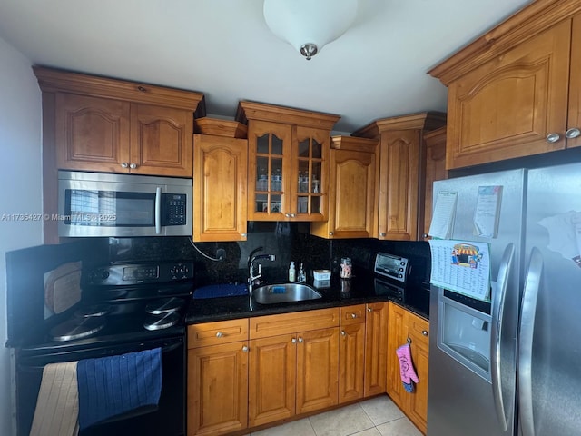 kitchen featuring sink, light tile patterned floors, dark stone countertops, backsplash, and stainless steel appliances