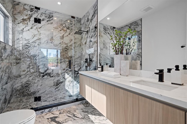 bathroom with tiled shower, vanity, and toilet