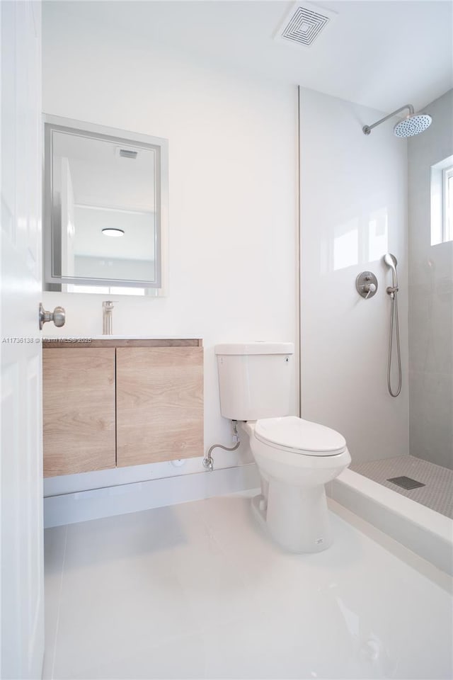 bathroom with vanity, a tile shower, tile patterned floors, and toilet