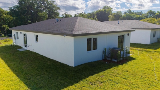 rear view of house featuring central AC and a yard