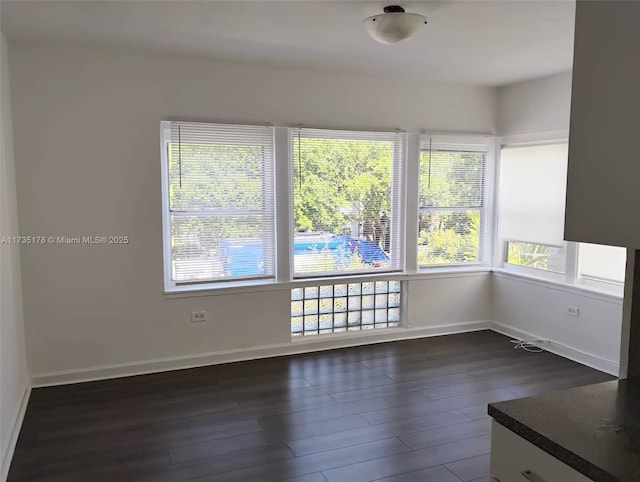 unfurnished room with baseboards and dark wood finished floors