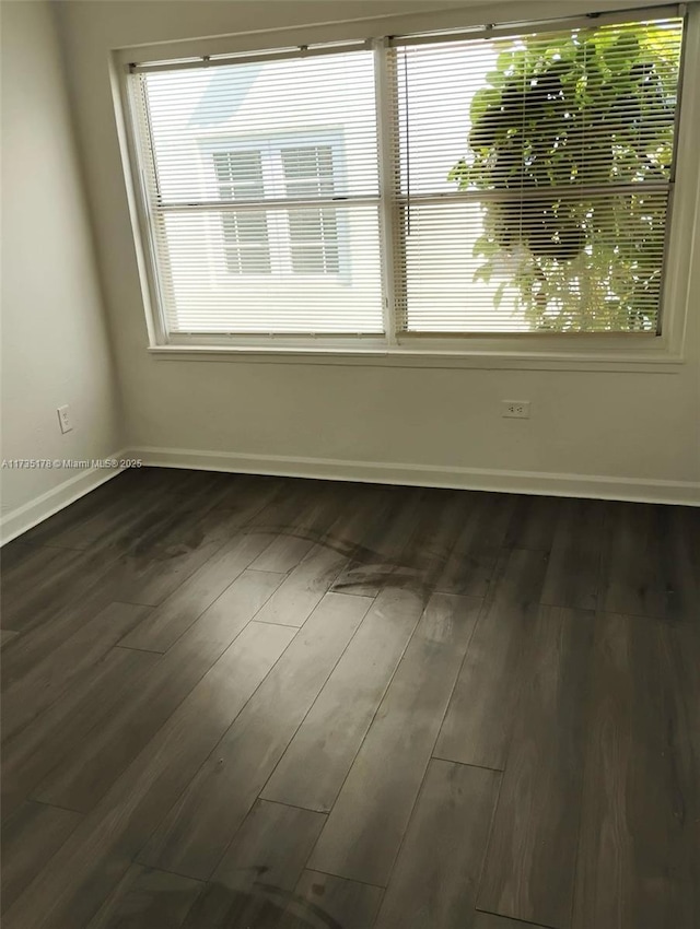 empty room with baseboards and dark wood-style flooring