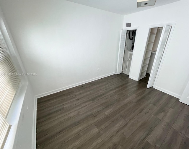 unfurnished bedroom featuring dark wood-type flooring, baseboards, and visible vents