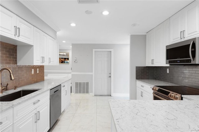 kitchen featuring sink, white cabinetry, light stone counters, appliances with stainless steel finishes, and decorative backsplash