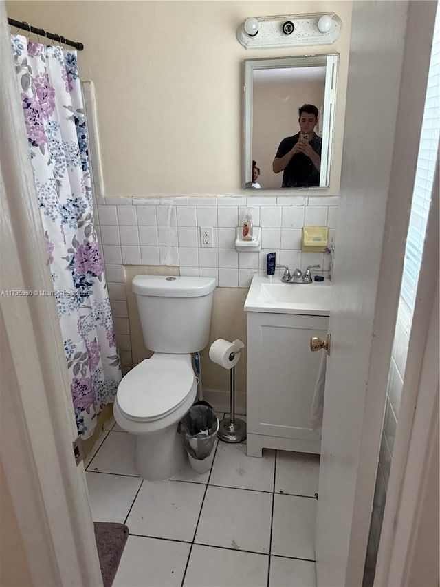 bathroom with tile walls, a shower with shower curtain, vanity, tile patterned floors, and toilet