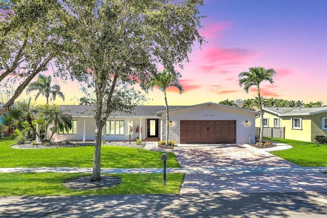 ranch-style home with a garage and a yard