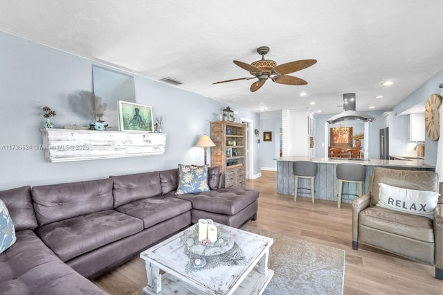 living room featuring ceiling fan, sink, light hardwood / wood-style floors, and a textured ceiling