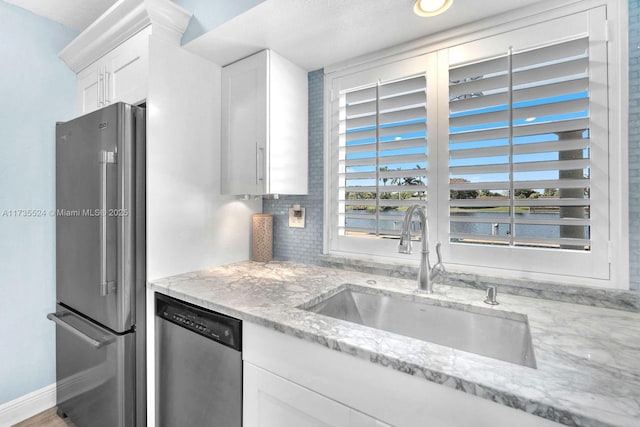 kitchen with white cabinetry, appliances with stainless steel finishes, sink, and light stone counters